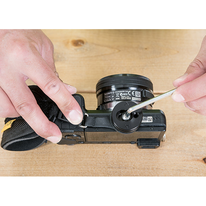 Camera hand strap being attached to a camera with an allen wrench