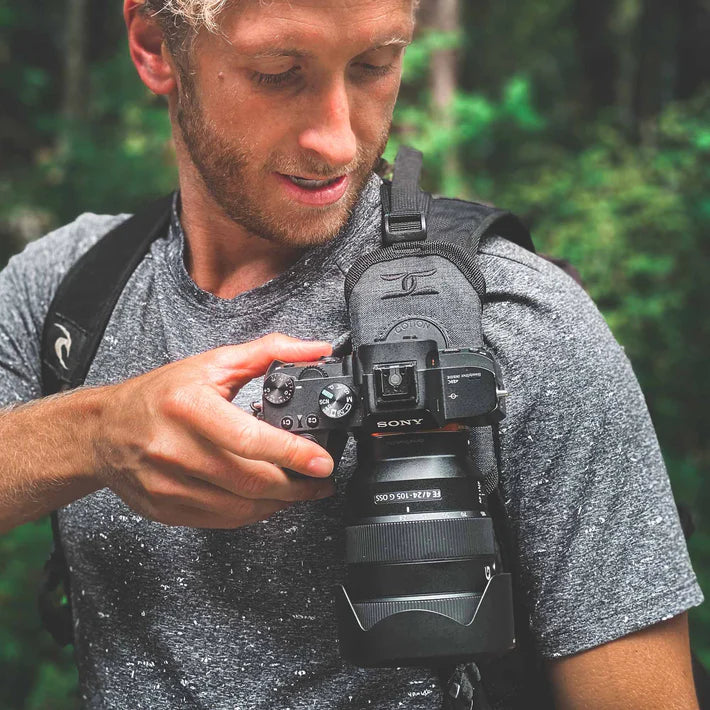 Photographer viewing an image on his camera mounted in a camera strap holster