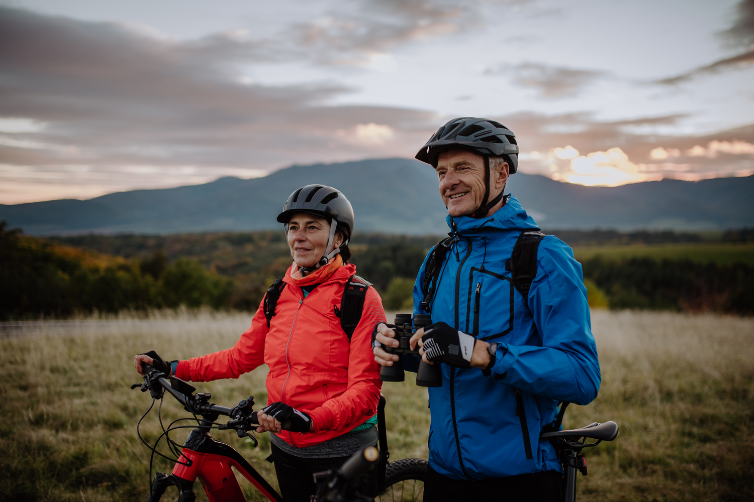 Couple biking with binocular straps in the wild